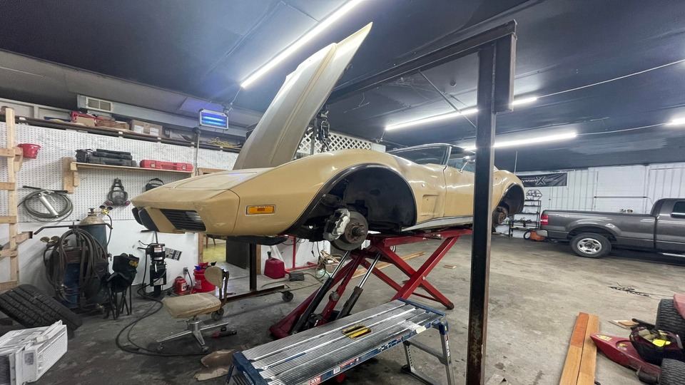 A classic sports car up on the lift inside Rockstar Auto Repair