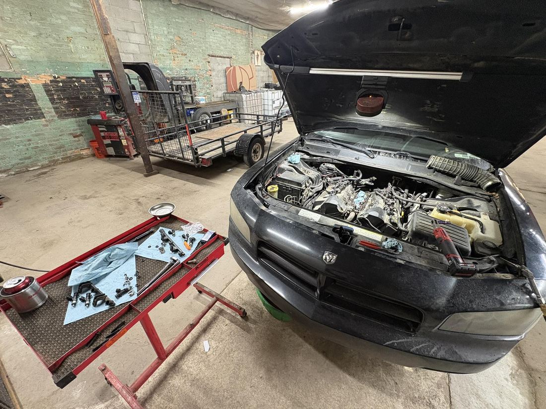 An engine bay open for service with parts laid out on a tray