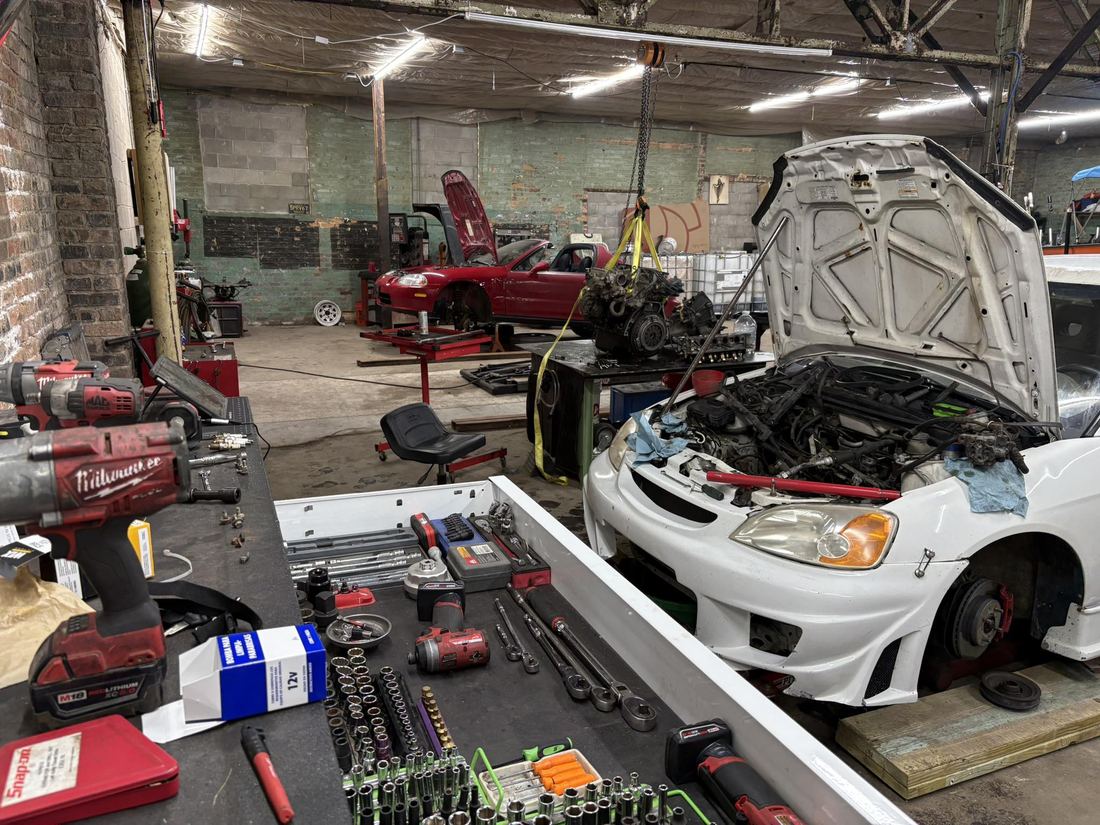 The shop floor with a car hood up and tools laid out
